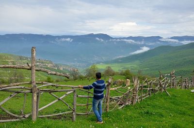 Rear view of man standing on mountain against sky