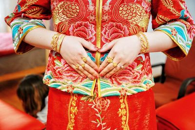 Midsection of a woman wearing traditional clothing forming heart