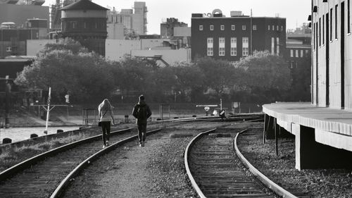 Rear view of people on railroad tracks in city