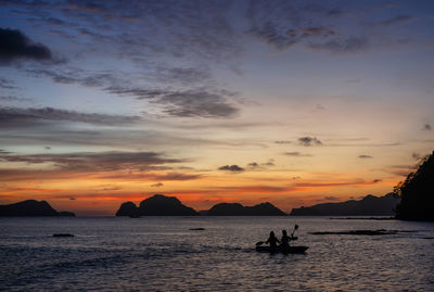 Silhouette boats in sea against sky during sunset