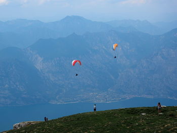 People paragliding over mountain against sky