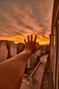 Person hand against orange sky