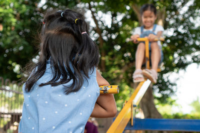 Low angle view of friends playing on seesaw at playground