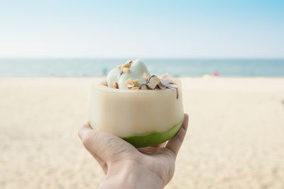 Close-up of hand holding ice cream cone on beach