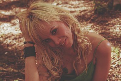 Portrait of smiling woman with hand in hair relaxing on field