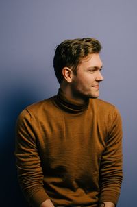 Young man looking away against white background