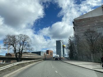 Road by buildings in city against sky