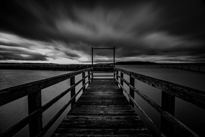 Empty pier over sea against sky