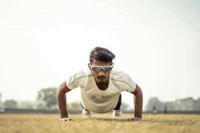 Close up portrait of a young indian sportsman exercising in the field. sportsman doing push ups