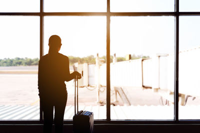 Rear view of silhouette woman standing at airport terminal