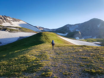 Rear view of man standing on mountain against sky