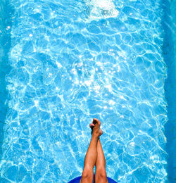 Low section of person relaxing in swimming pool