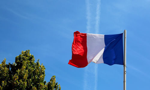 Low angle view of flag against blue sky