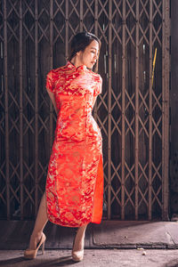 Woman standing against red wall