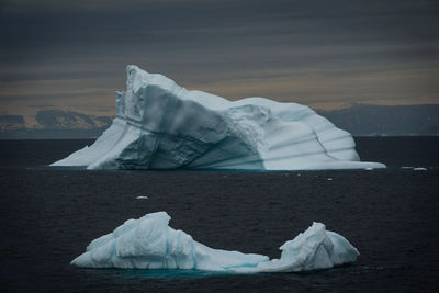 Ice floating on sea against sky during winter