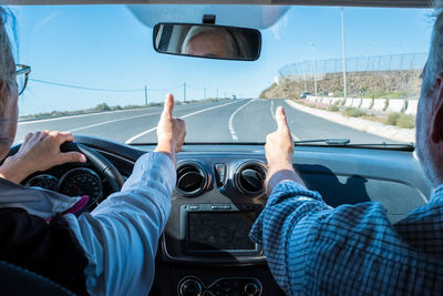 Senior couple showing thumbs up sign in car