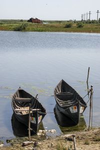 Boat moored on lake against sky