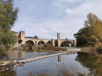 Arch bridge over river against sky