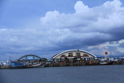 Suspension bridge over sea against cloudy sky