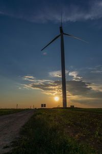 Windmill on field against sky during sunset