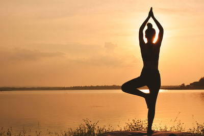 Silhouette of woman doing yoga against sky during sunset