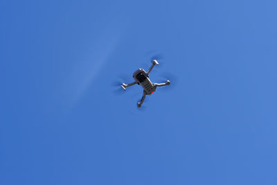 Low angle view of bird flying against clear blue sky