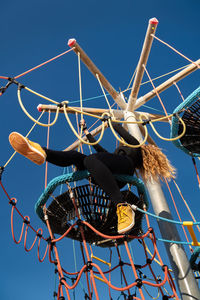 Low angle view of woman sitting on amusement park ride against sky