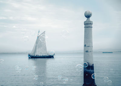 Lighthouse and boat on sea against sky