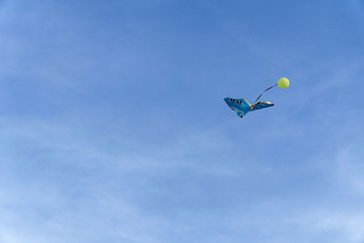 Low angle view of balloons flying against blue sky