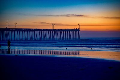 Pier over sea against sky during sunset