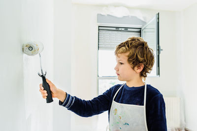 Portrait of boy standing against wall at home