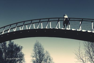 Low angle view of woman standing by bridge against sky