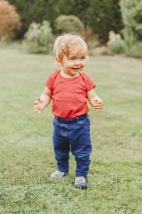 Baby girl smiling while standing on grassy field