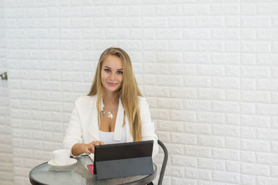 Portrait of young businesswoman sitting at table in office