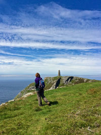 Man on rock by sea against sky