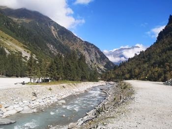 Scenic view of river by mountains against sky