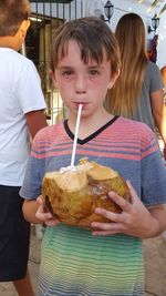 Portrait of boy having coconut while standing outdoors