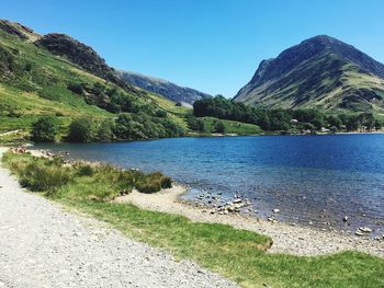 Scenic view of lake and mountains against clear blue sky