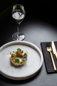 Appetizing snack with crab near decorated with cucumber rolls and caviar served on black background with cutlery in restaurant