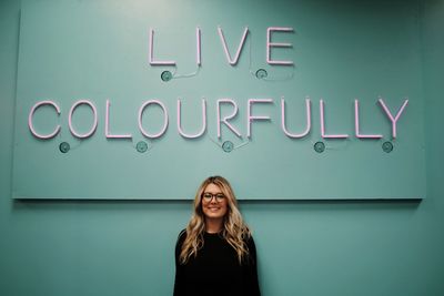 Portrait of a smiling young woman against wall