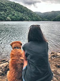 Rear view of man with dog looking at lake