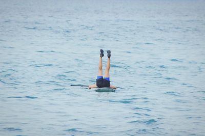 Low section of man with feet up paddleboarding in sea