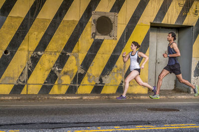 Female and male runners train on industrial city street in brooklyn