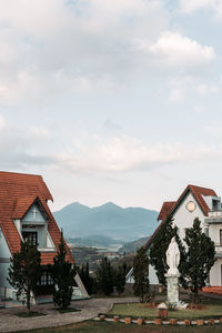 Houses by buildings against sky with mountain range in background