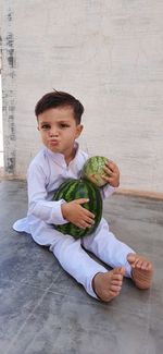 Full length of cute boy holding baby sitting on floor