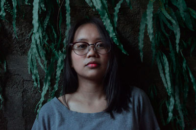 Portrait of young woman wearing eyeglasses by tree