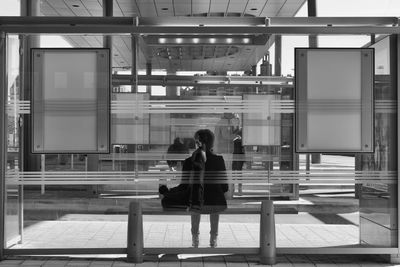 Rear view of woman sitting on bus stop