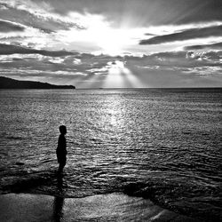 Silhouette man standing on beach against sky during sunset