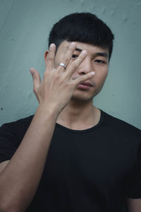 Portrait of young man standing against wall