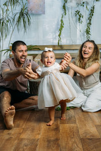 Cheerful couple playing with daughter at home